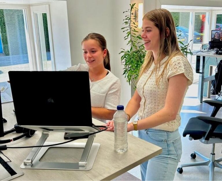 Twee collega's staan bij bureau en kijken naar computer.