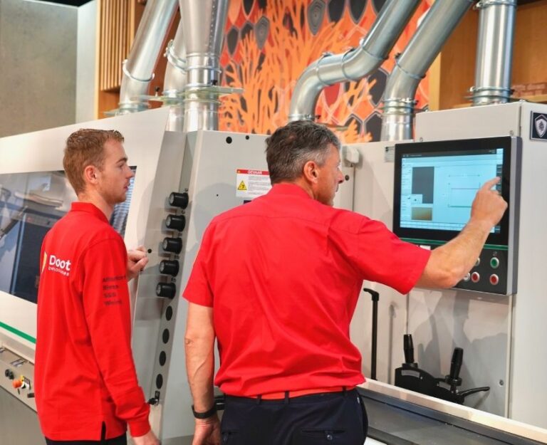 Collega kijkt met andere collega mee bij cnc-machine in showroom