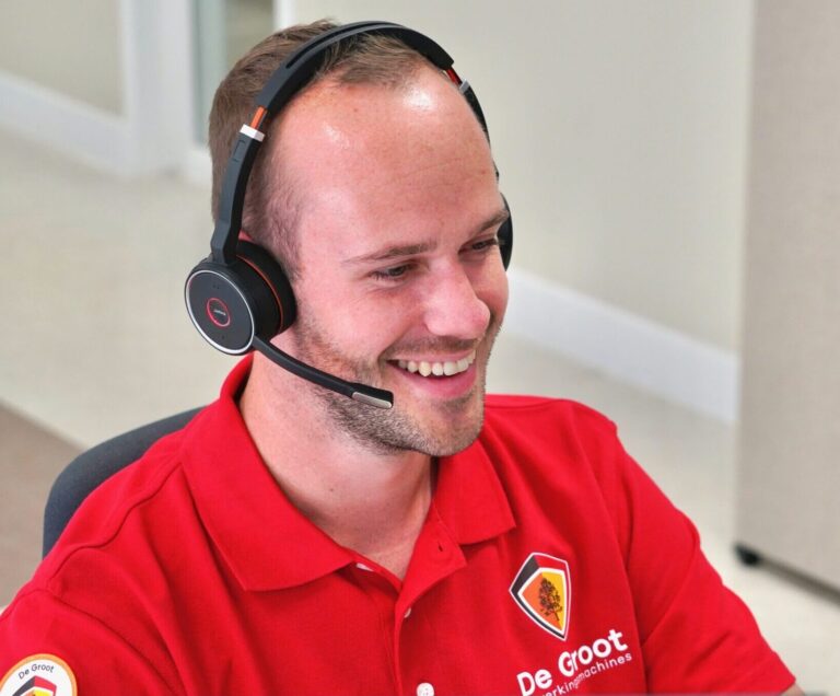 Servicecenter technicus werkt achter computer met headset op serviceafdeling