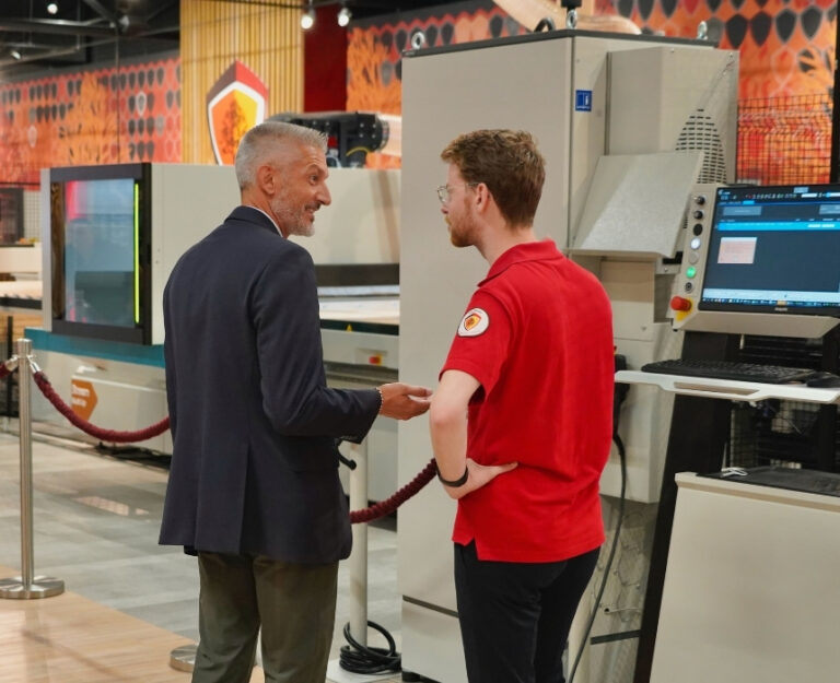 Collega luistert naar klant bij cnc-machine Biesse in de showroom.