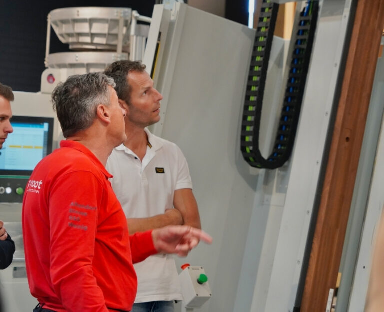 Collega geeft uitleg over cnc-machine aan de klant in de showroom.
