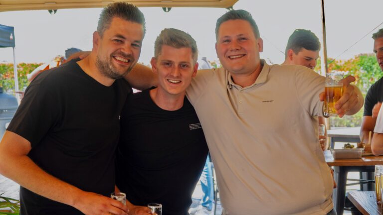 Drie collega's omhelzen elkaar op bedrijfsfeest.