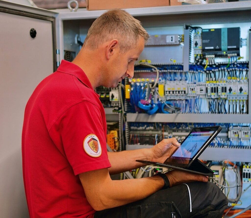Servicetechnicus werkt in cnc-machine op locatie en kijkt naar Ipad.