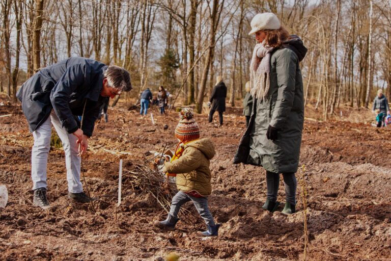 collega met familie plant een boom tijdens de boom plant dag in De Groot bos.