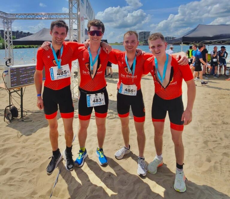 vier De Groot'ers staan bij finish bij sportevenement in De Groot sportkleding.