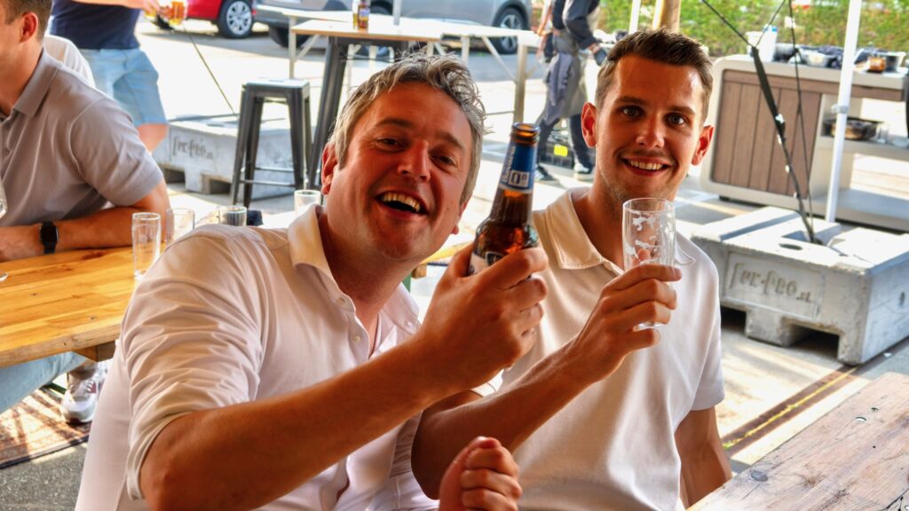 Twee collega's lachen met drinken in hun hand