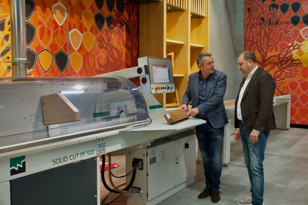 Accountmanager staat bij cnc-machine in de showroom met collega