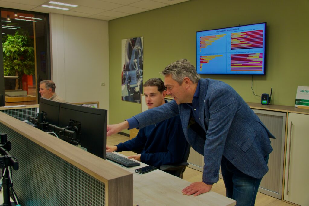 Accountmanager wijst naar computer met collega op kantoor.