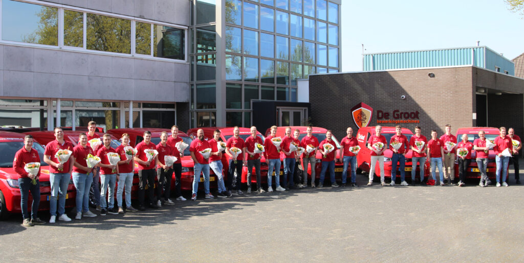 Team servicetechnici met bloemen in hand bij auto's