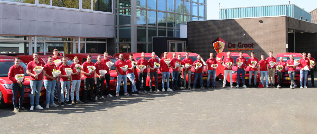 Team servicetechnici met bloemen in hand bij auto's