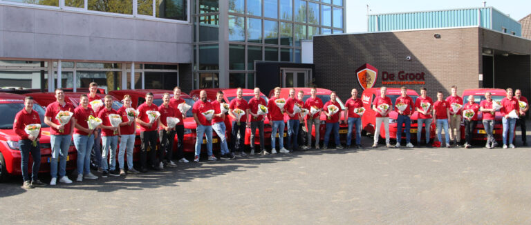 Team servicetechnici met bloemen in hand bij auto's